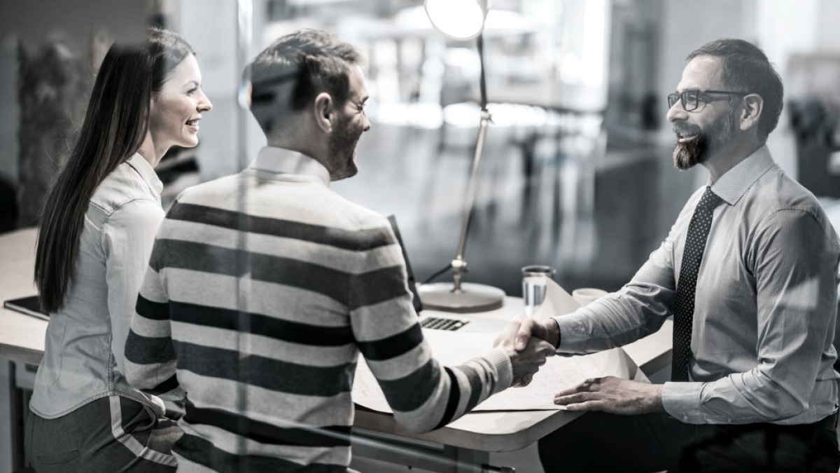 happy-couple-shaking-hands-with-real-estate-agent-in-the-office-picture-id1093900326